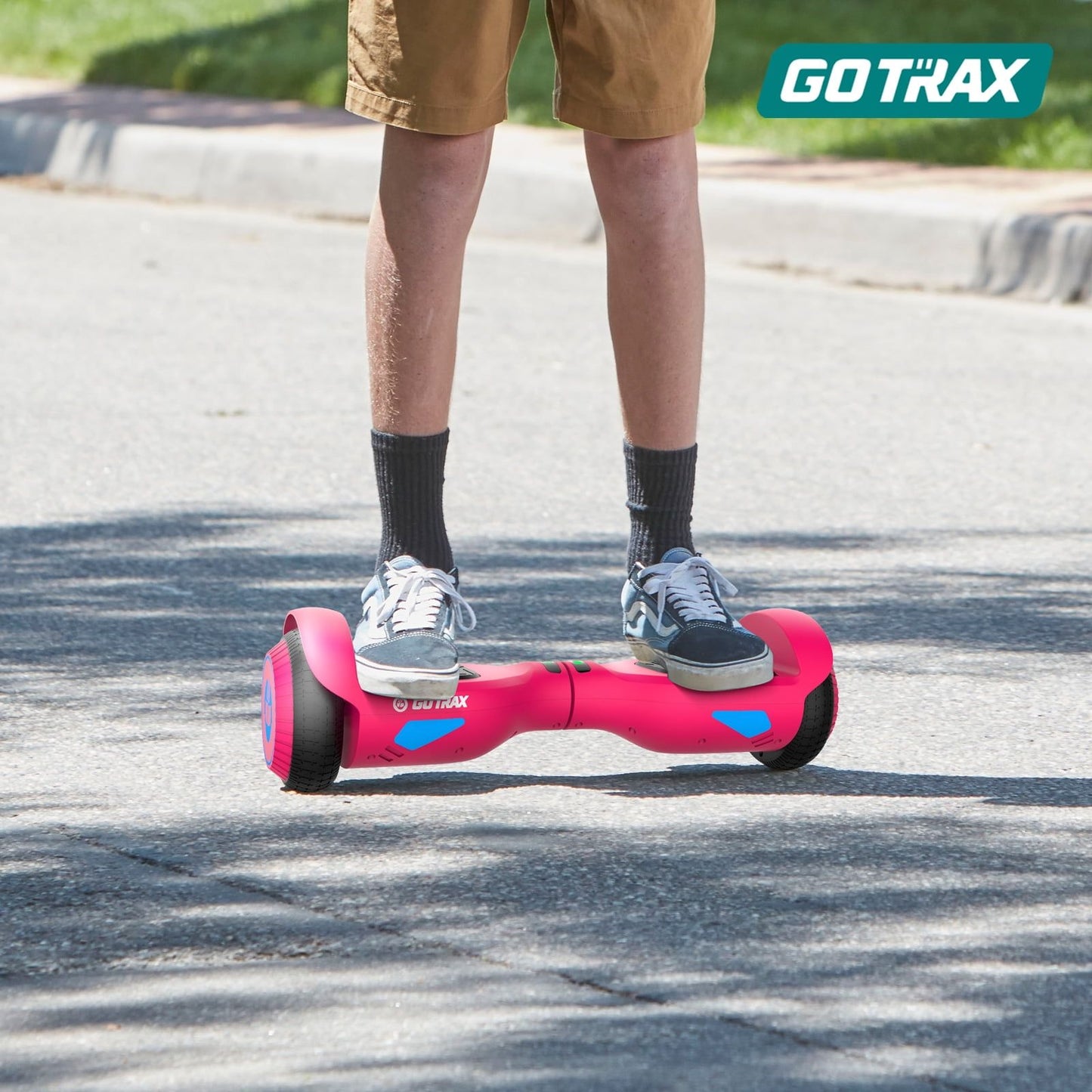 Person riding a pink hoverboard on a road with 'GOTRAX' branding.