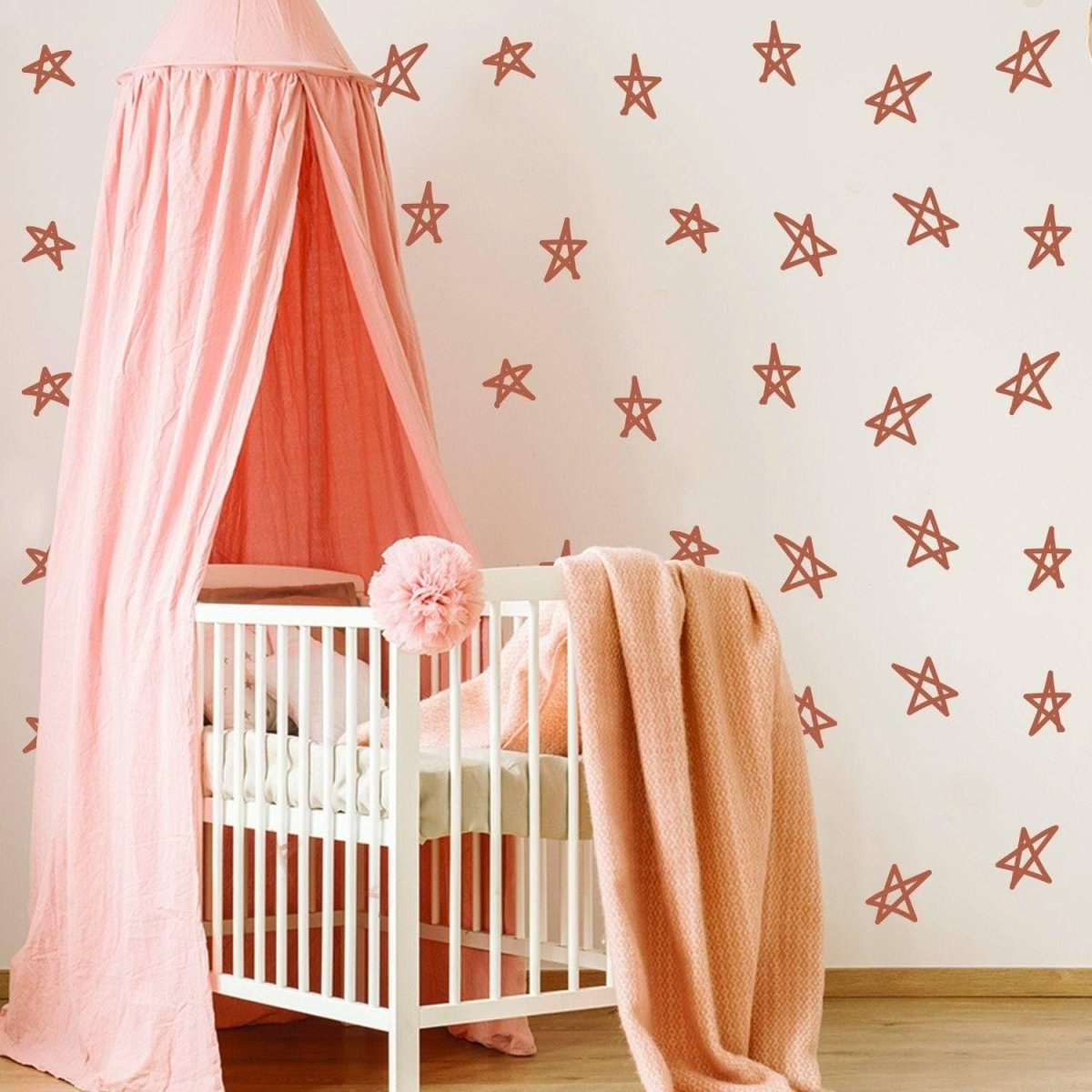 Nursery room with a crib, pink canopy, and star-patterned wall.
