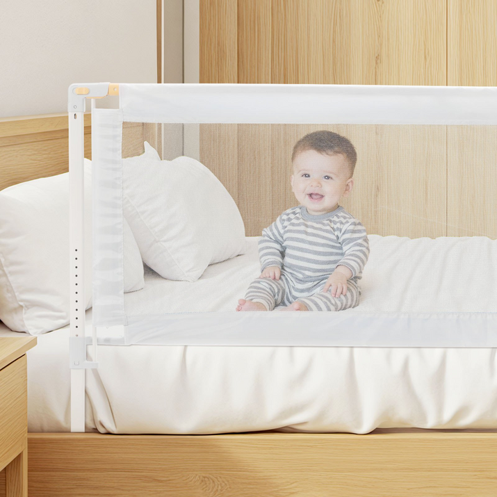 Child sitting on a bed with a safety rail in a bedroom setting