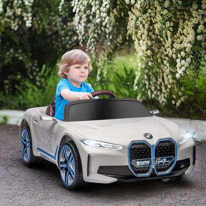 Child driving a toy BMW car in a garden setting