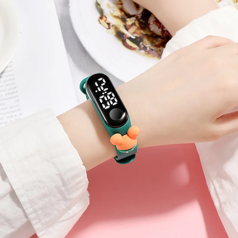 Digital wristband with a green strap featuring cartoon characters on a white background