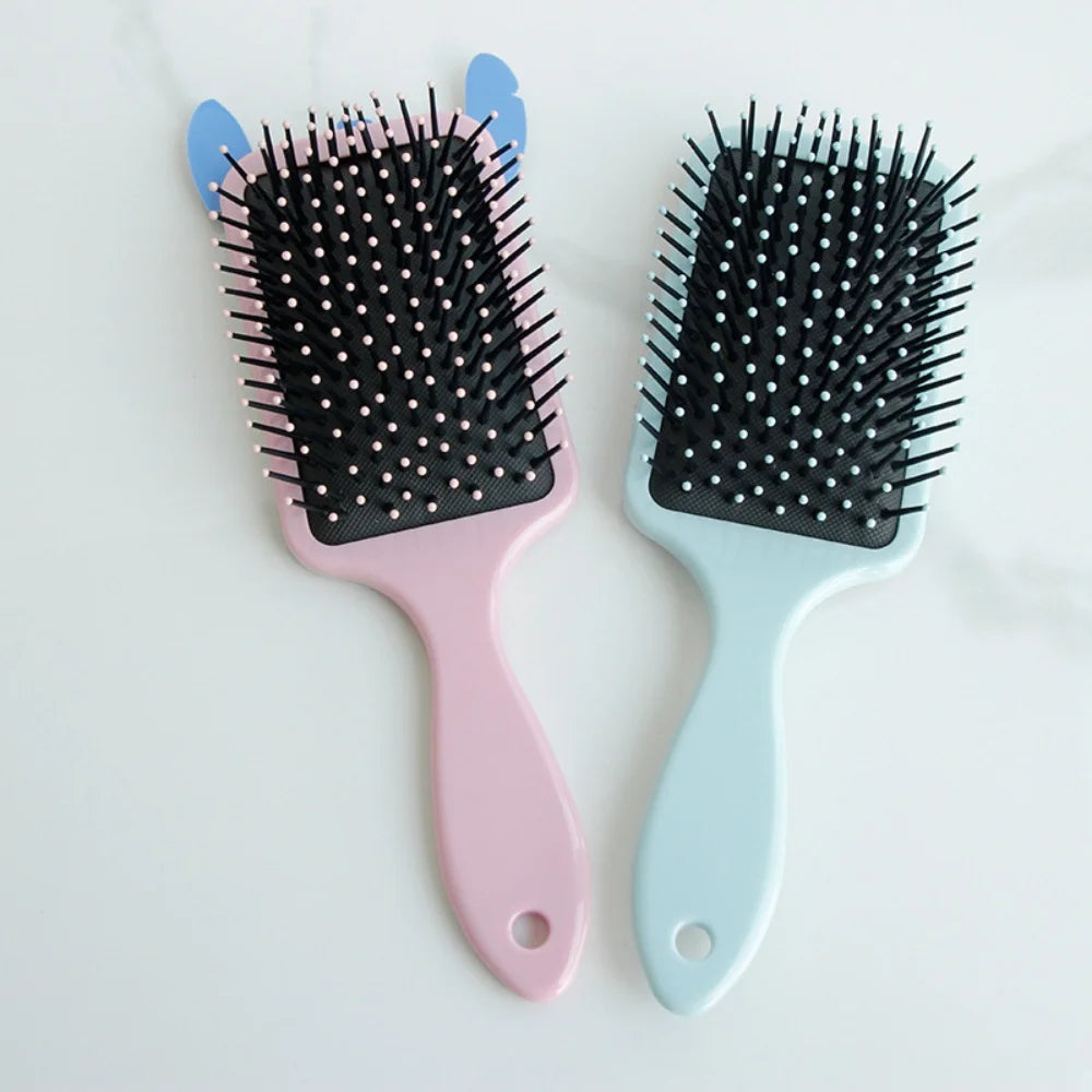 Two hairbrushes, one pink and one blue, with black bristle heads on a white background.
