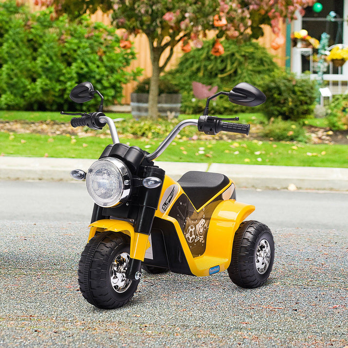 Yellow and black toy motorcycle on a road with greenery in the background