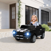 Child sitting in a black toy car with glowing headlights in front of a house.