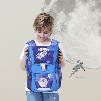 Child holding a blue backpack with space-themed design, standing against a light gray background.