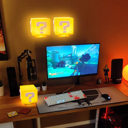 Gaming setup with question mark block lights and a monitor displaying a game.