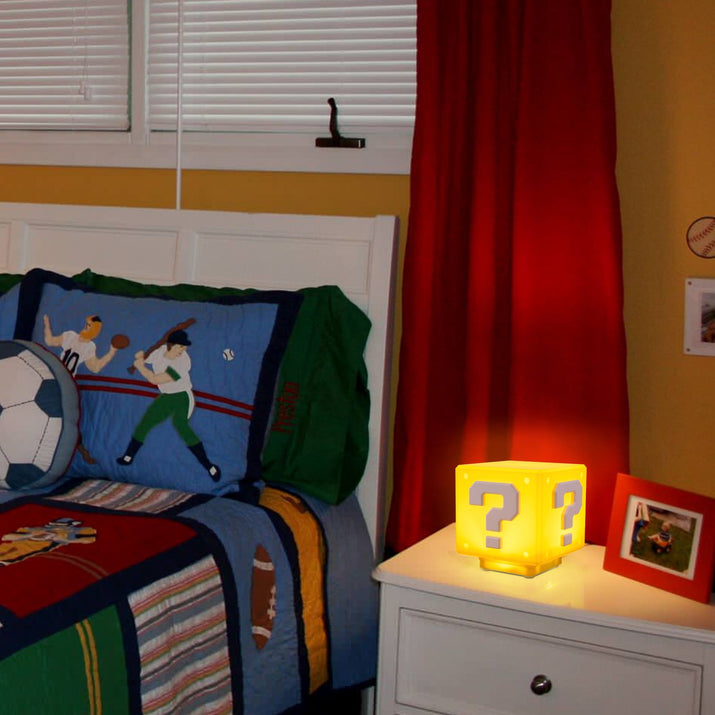 Children's bedroom with sports-themed bedding and a nightstand with a glowing lamp.