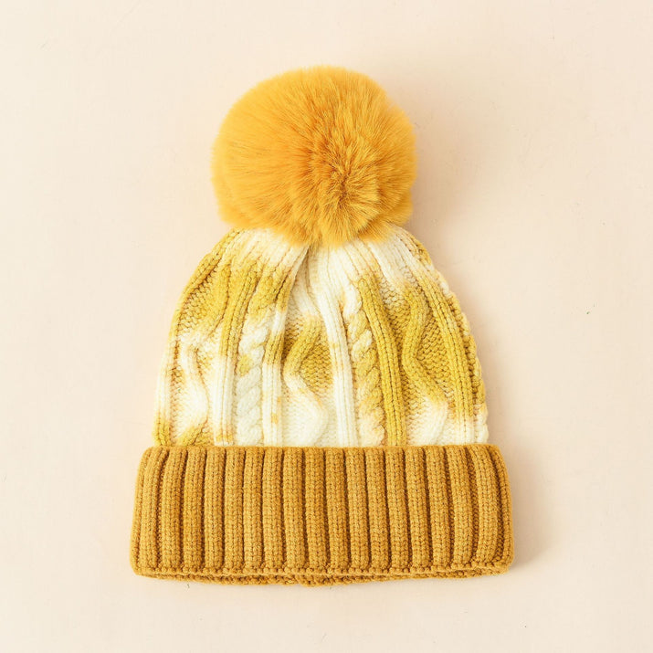 Yellow knit beanie with a pom-pom on a beige background