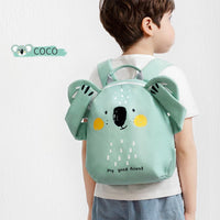 Child wearing a green koala backpack with 'COCO' branding on a white background
