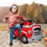 Child beside the red ride-on fire truck outdoors