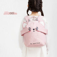 Child wearing a pink backpack with bear ears and face design on a white background