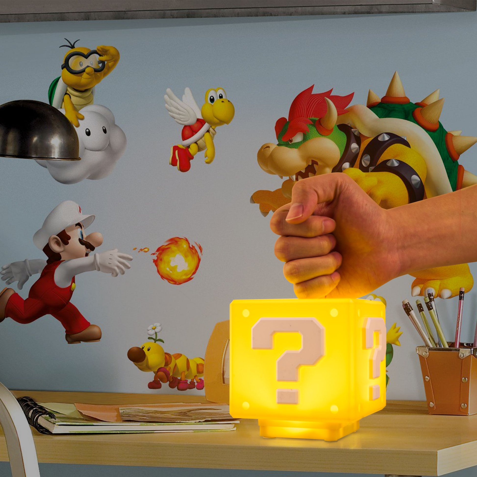 Hand holding a yellow lamp with a question mark, surrounded by cartoon characters on a wall.